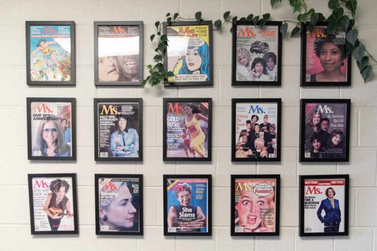 Fifteen magazines are hung on a wall, each with women on the cover.