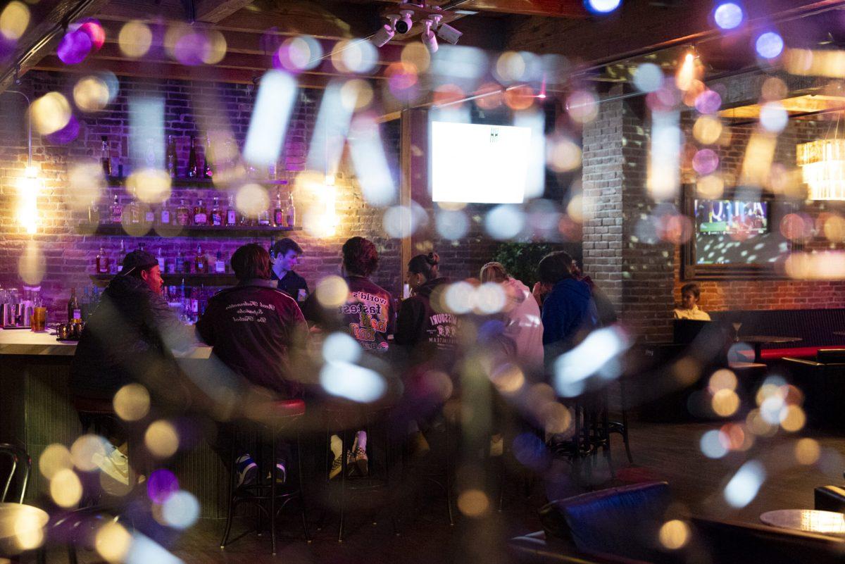 A group of people sit at a bar.