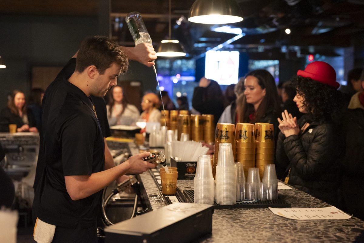 A man pours two drinks into two separate cups.