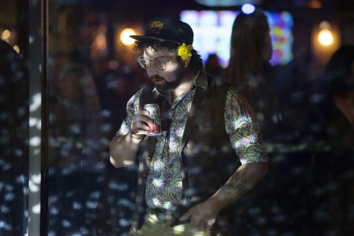 A man looks at a disco ball while holding a beer.