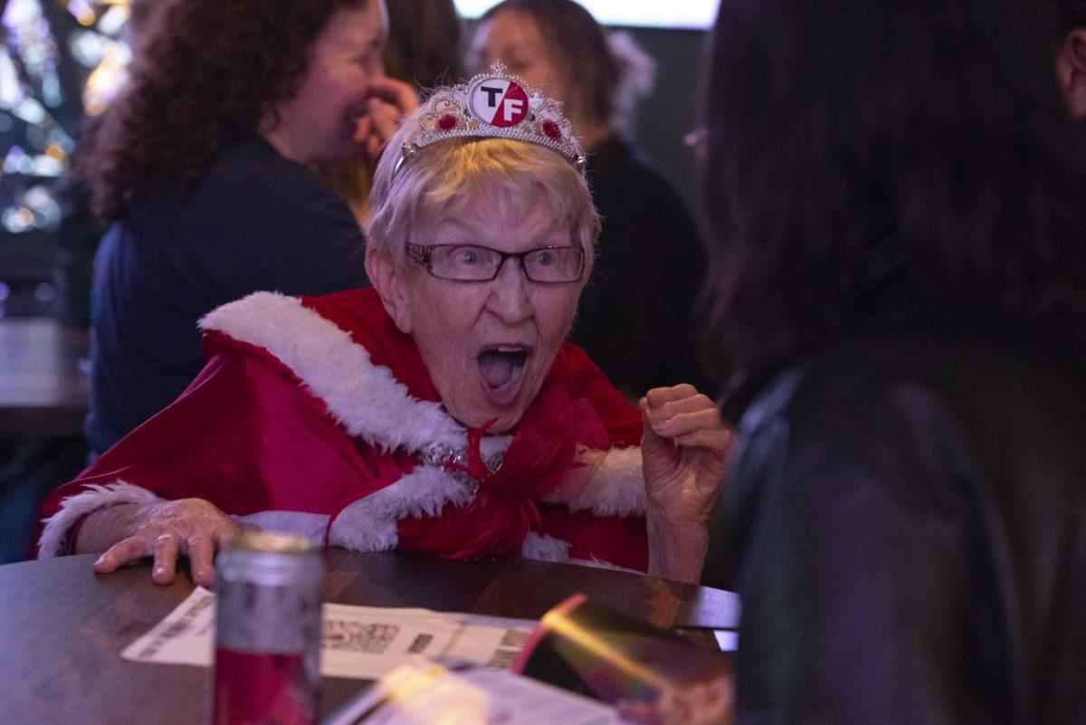 A lady shares conversation with someone at the bar.