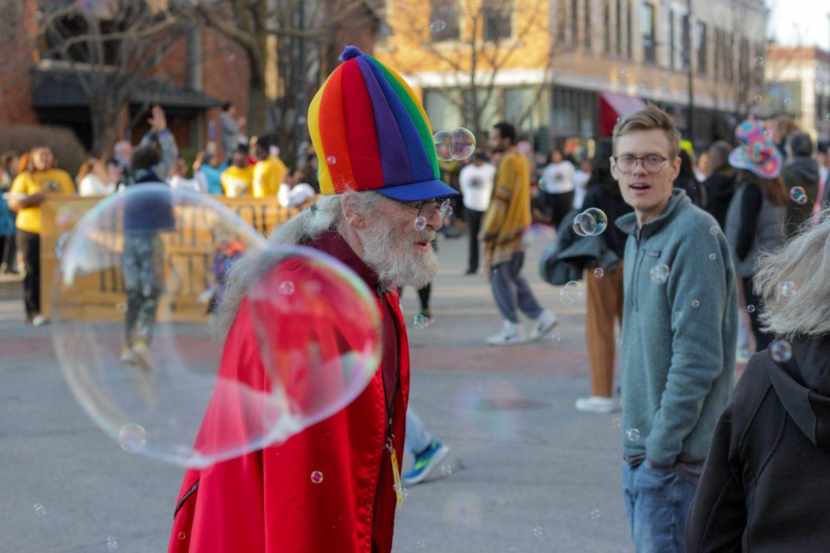 Man in a rainbow hat smiles.