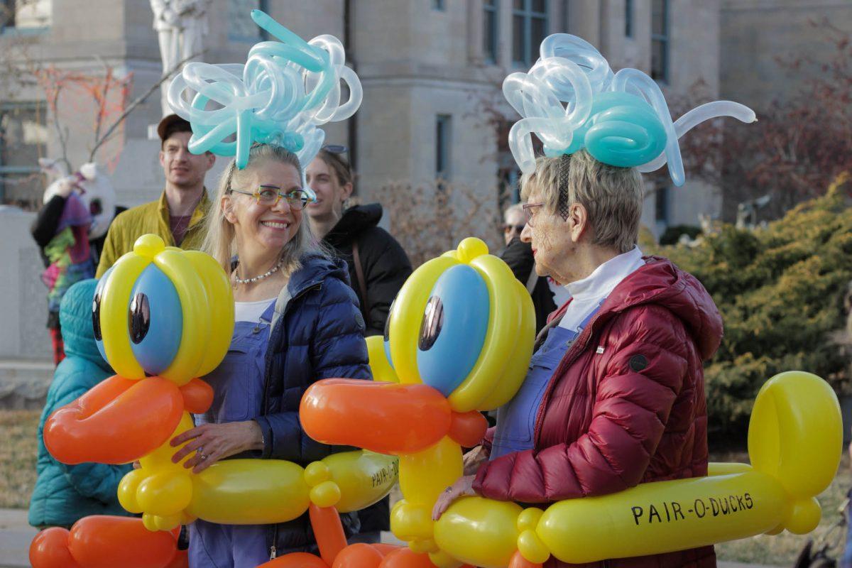 Two women in balloon duck costumes laugh with each other.
