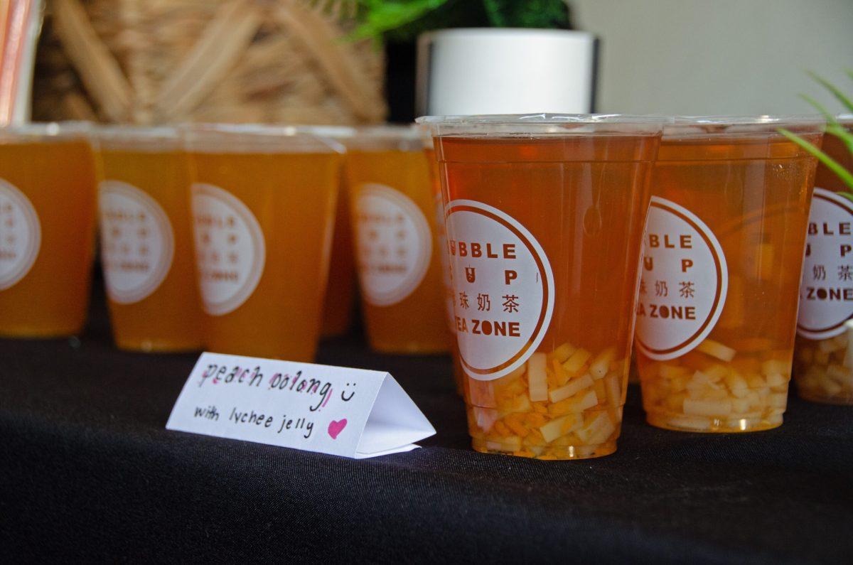 A table full of orange drinks is shown labeled, “peach oolong with lychee jelly.”
