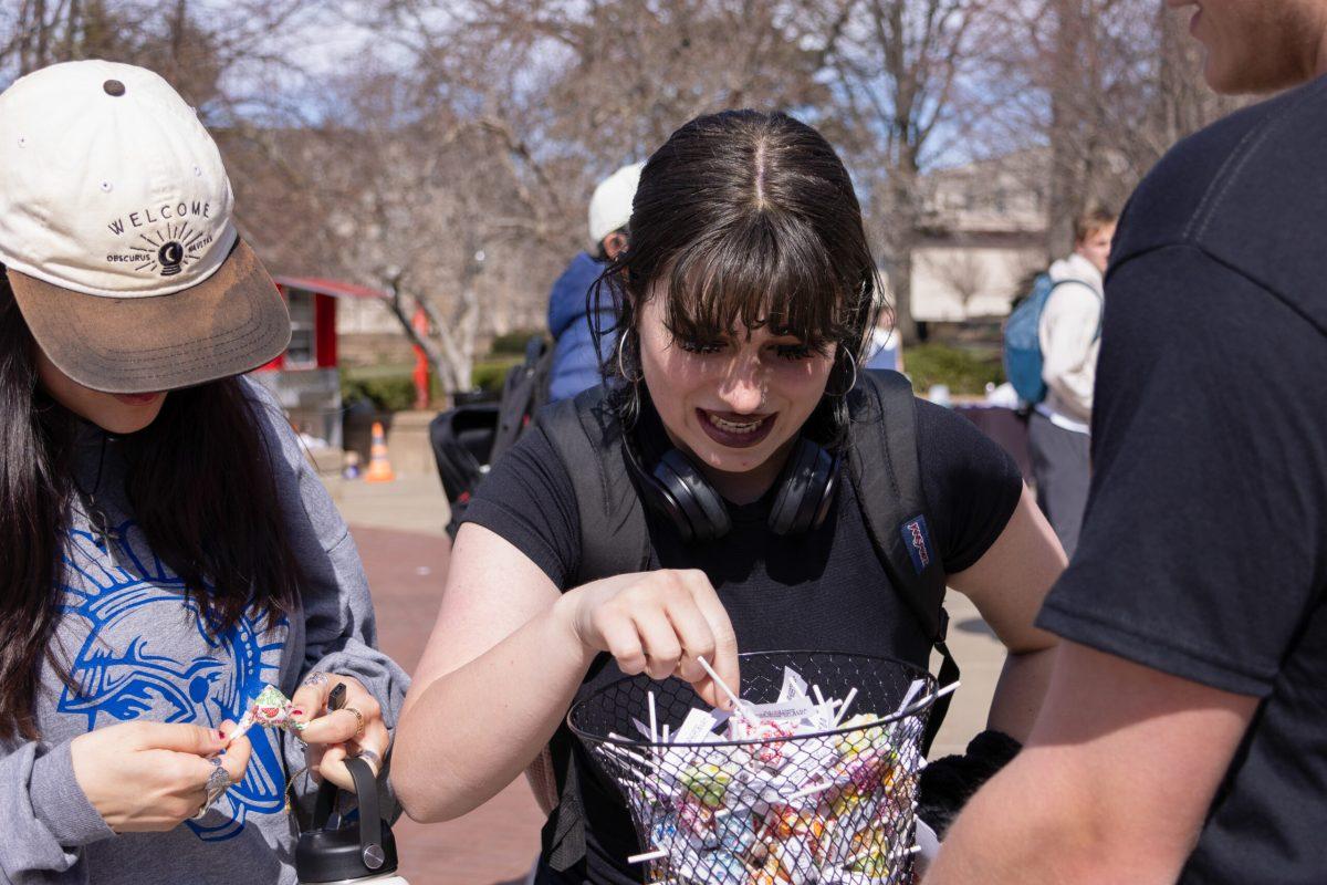 A student choosing a lollipop from All in 4 Mizzou’s candy basket.
