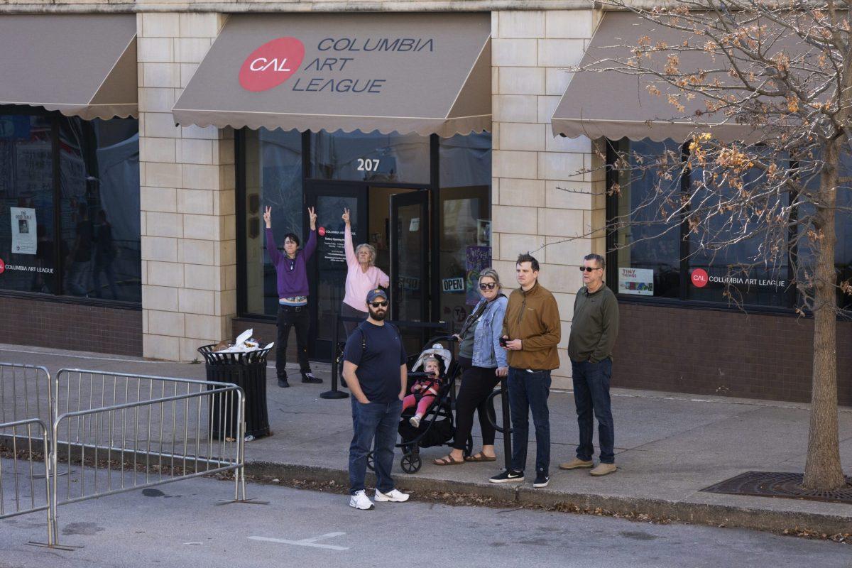 Onlookers hold up peace signs from across the street.

