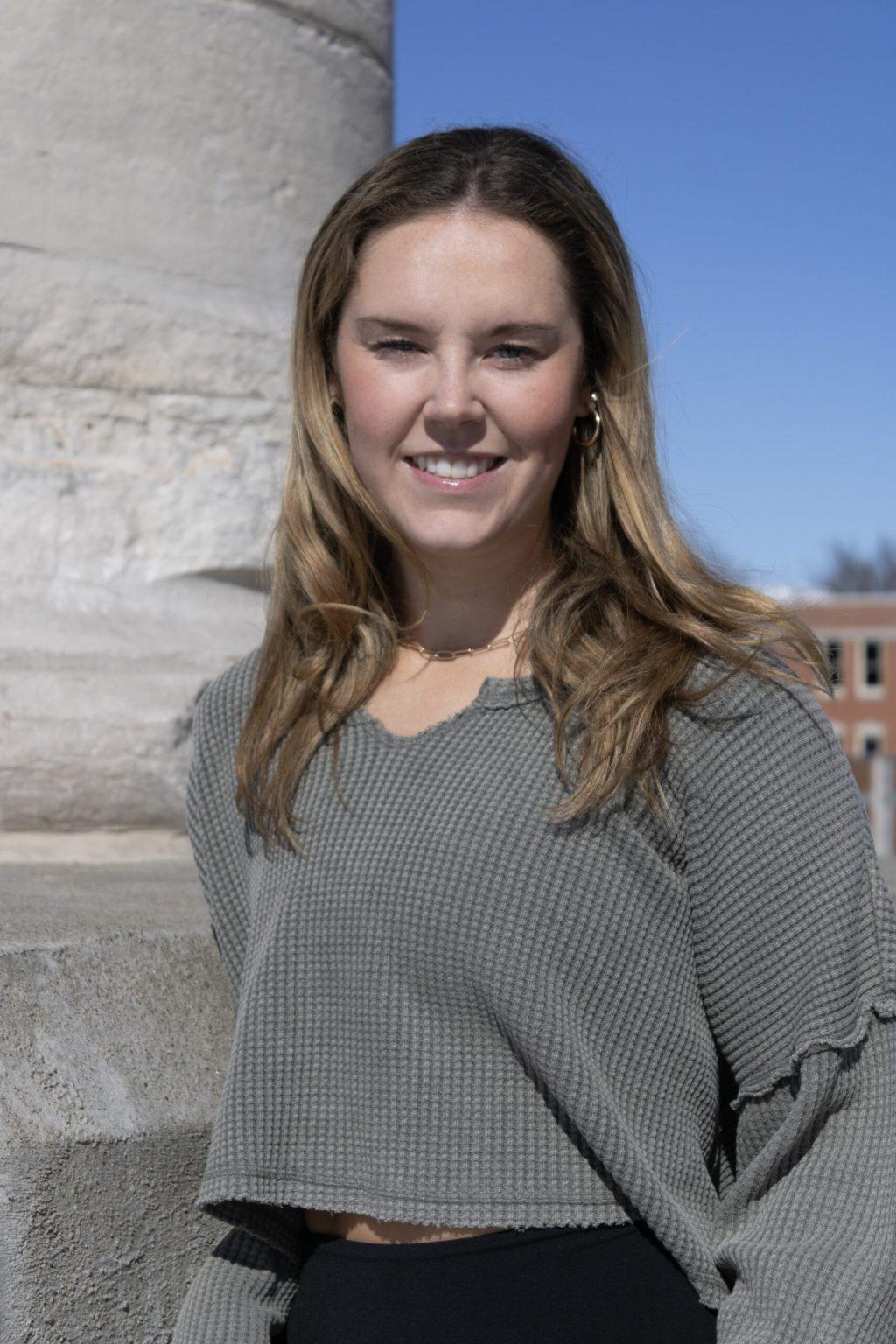 A girl leans against a column.