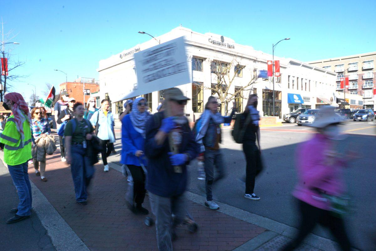 A group of people cross a street holding signs. 