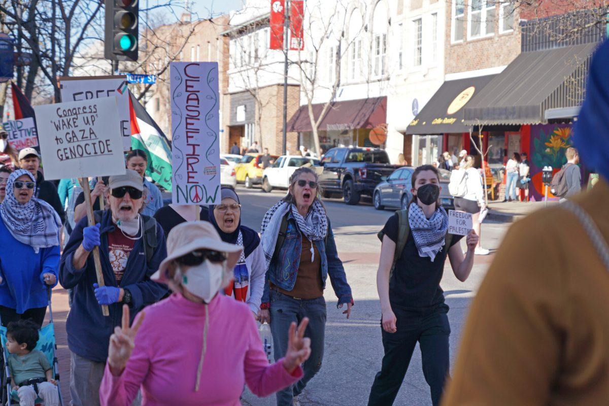 A crowd walks down a street with signs. 