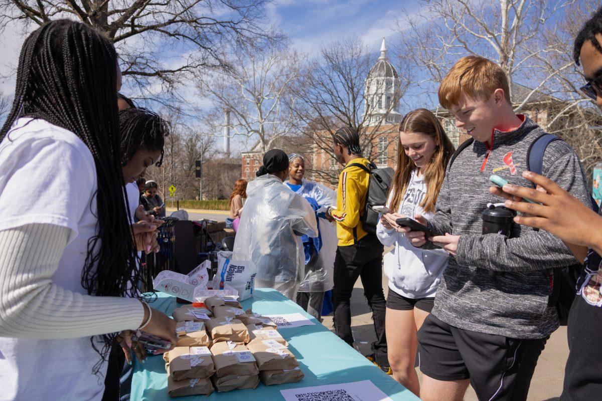 Two students looking at their phones in front of the Revive the Roar table.
