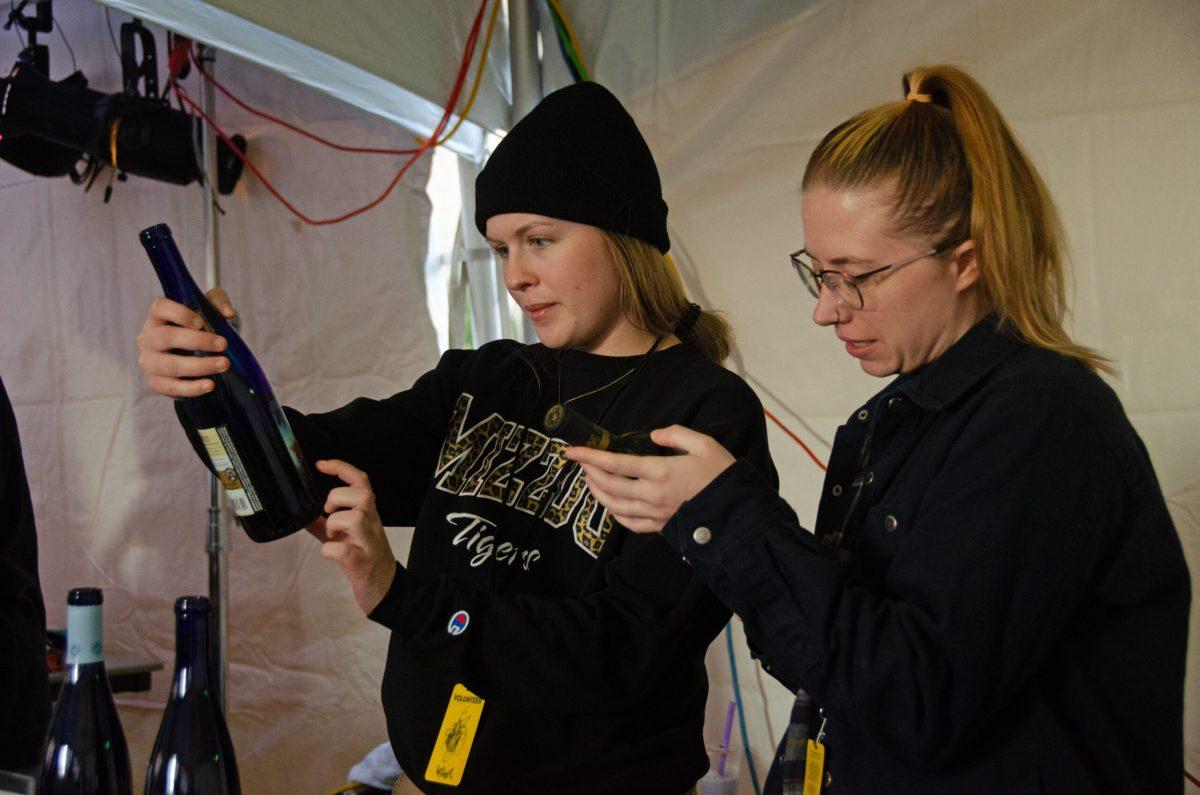 Two women look at bottles of wine.