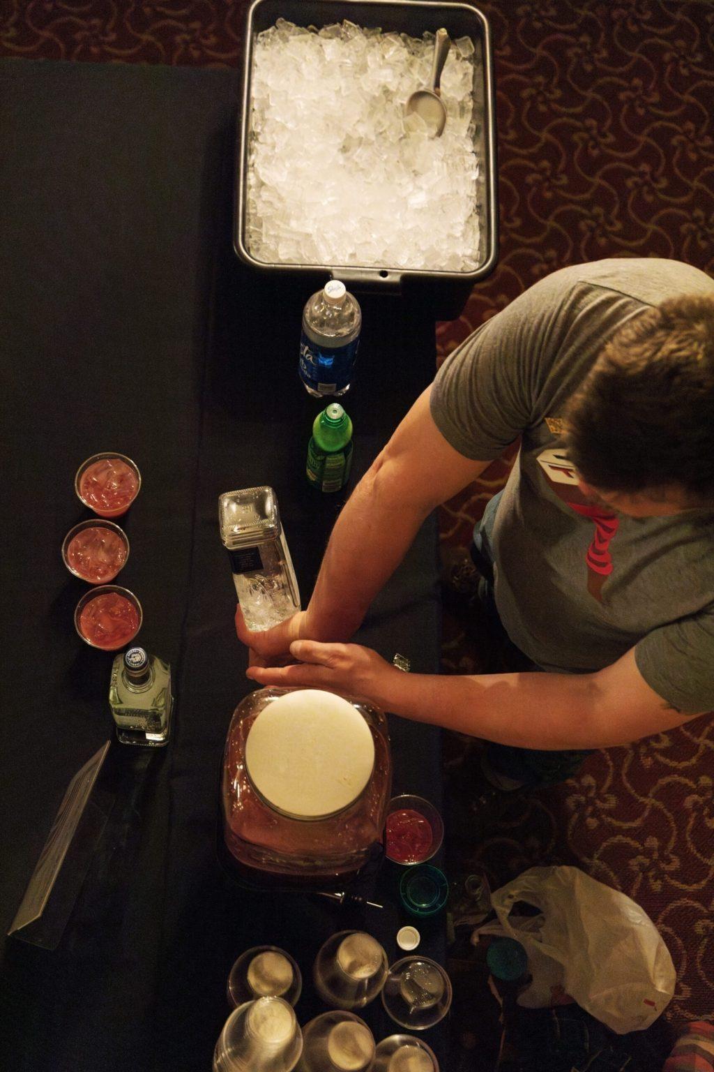 A bartender makes drinks on a black table. 