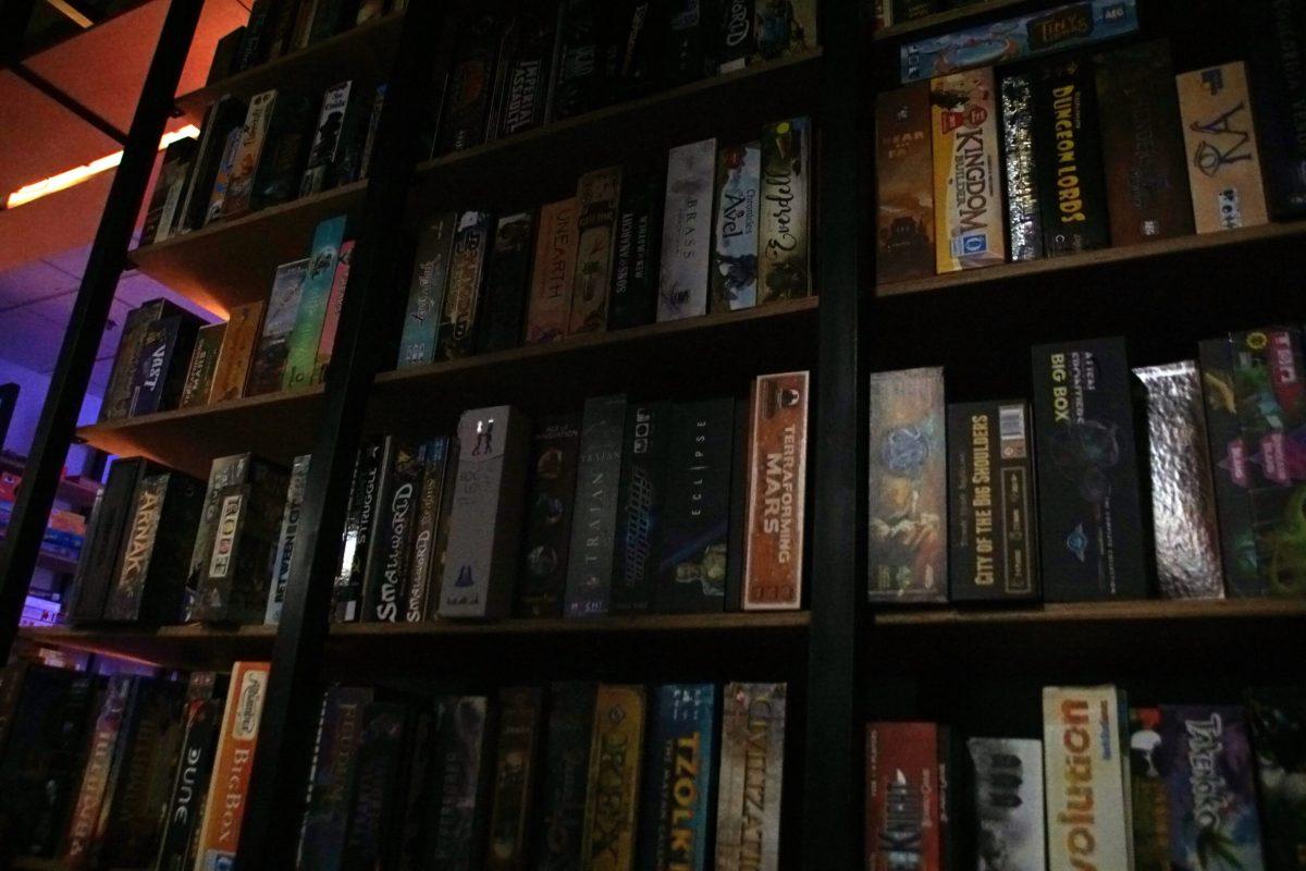 A shelf full of board games covers the wall.
