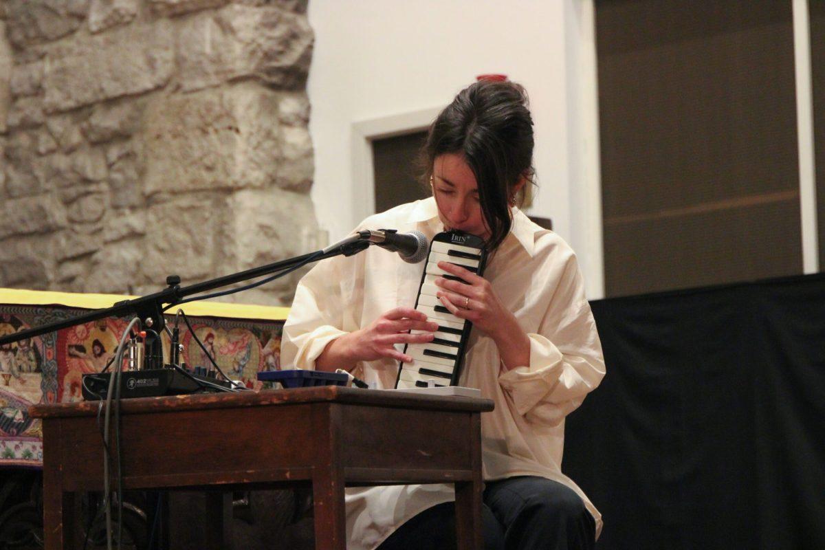 A woman is seen blowing into a melodica and using her fingers to press on the keys.