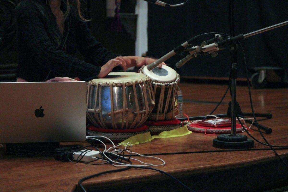 A detailed shot of the tabla drums with two mics angled towards them to amplify the sound. A MacBook is shown in the corner of the picture.