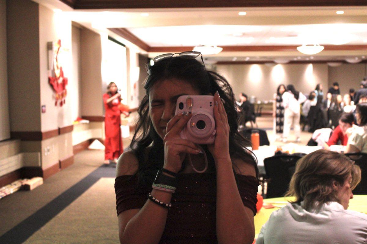 A girl takes a picture with a polaroid camera.