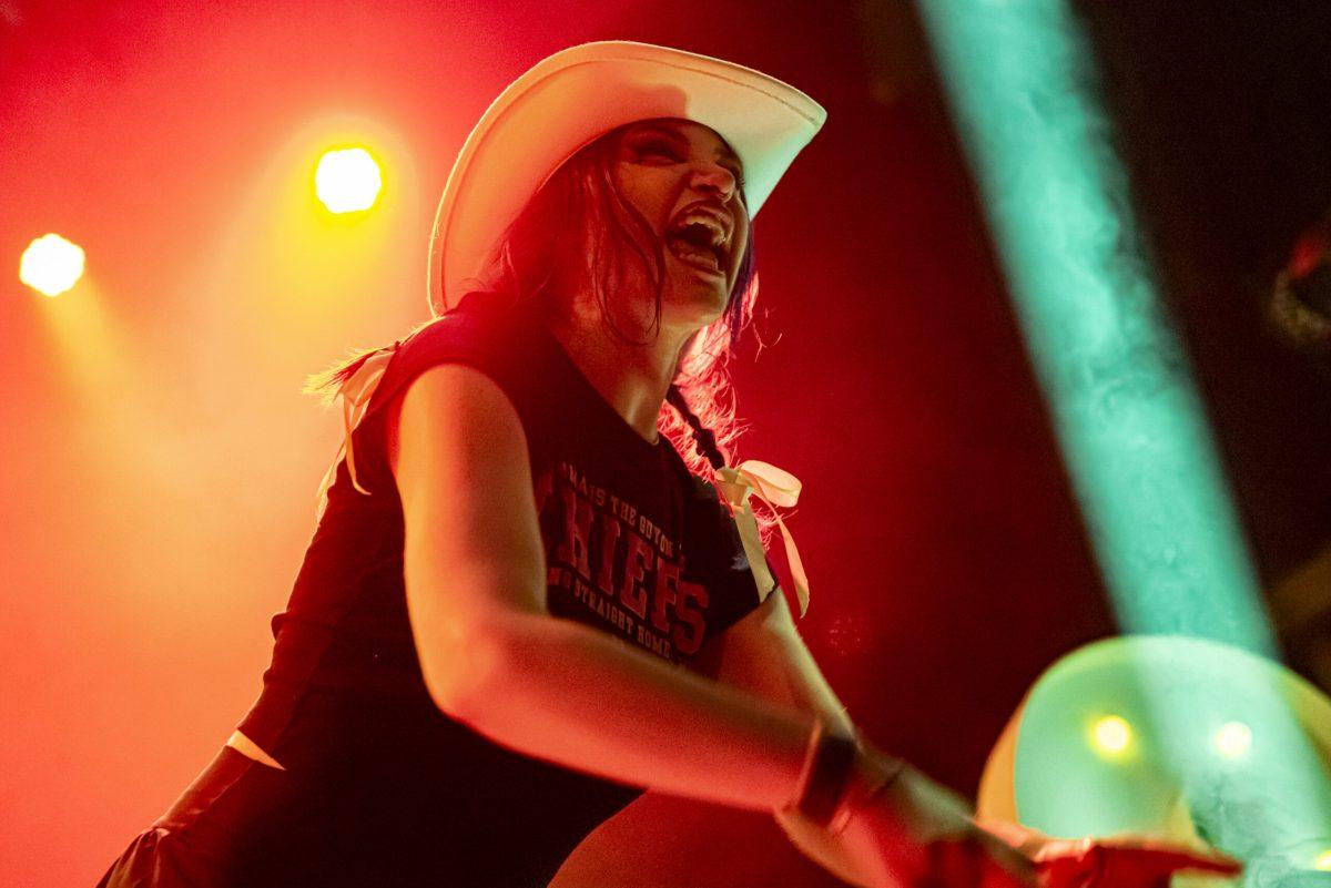 A woman in a white cowboy hat leans down to reach the crowd.