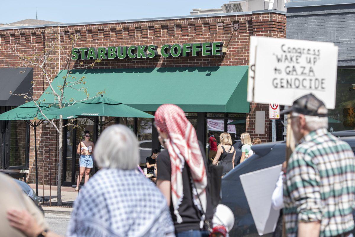 Protestors march past a sign that reads, “STARBUCKS COFFEE.”
