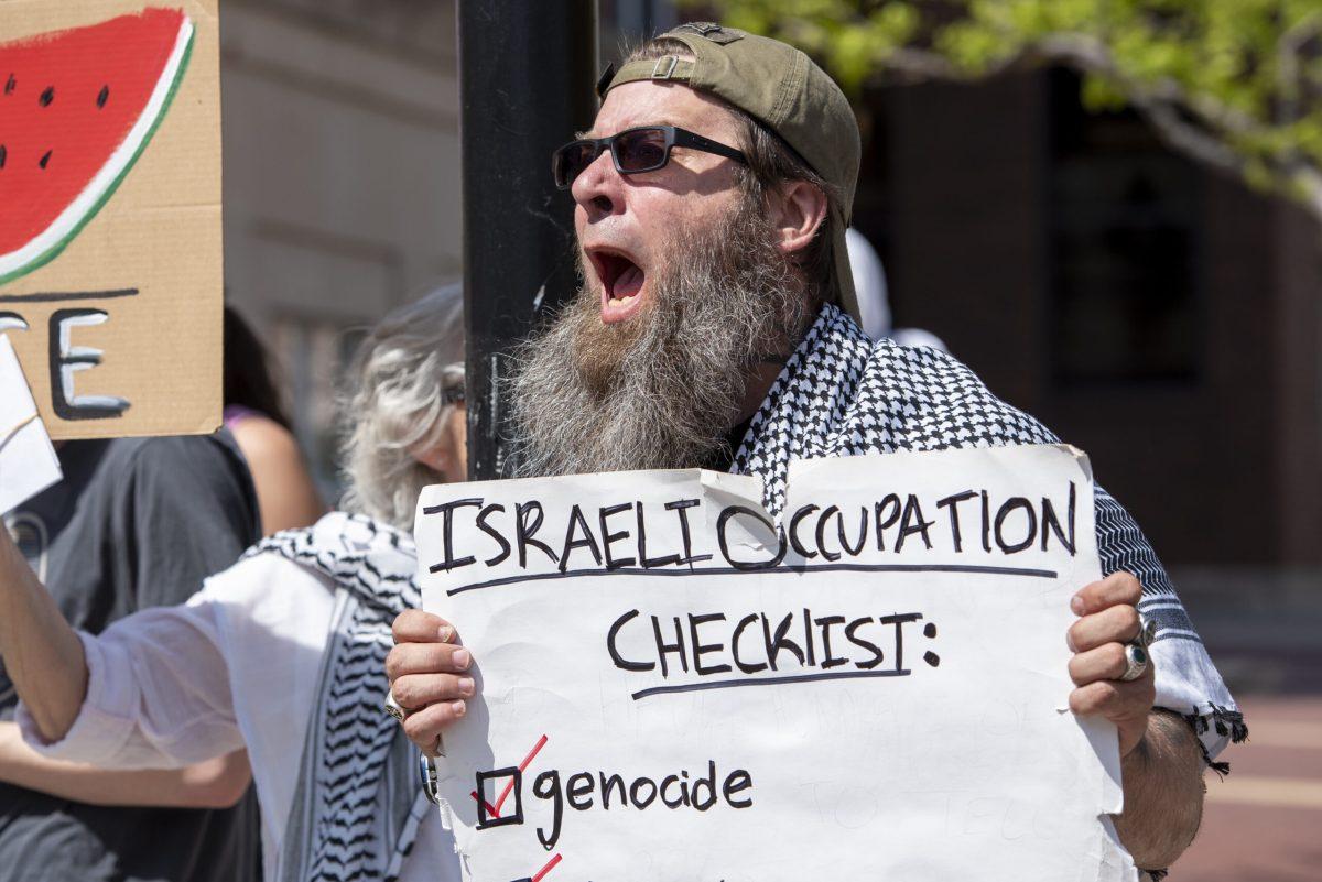 A protest holds up a sign while shouting.
