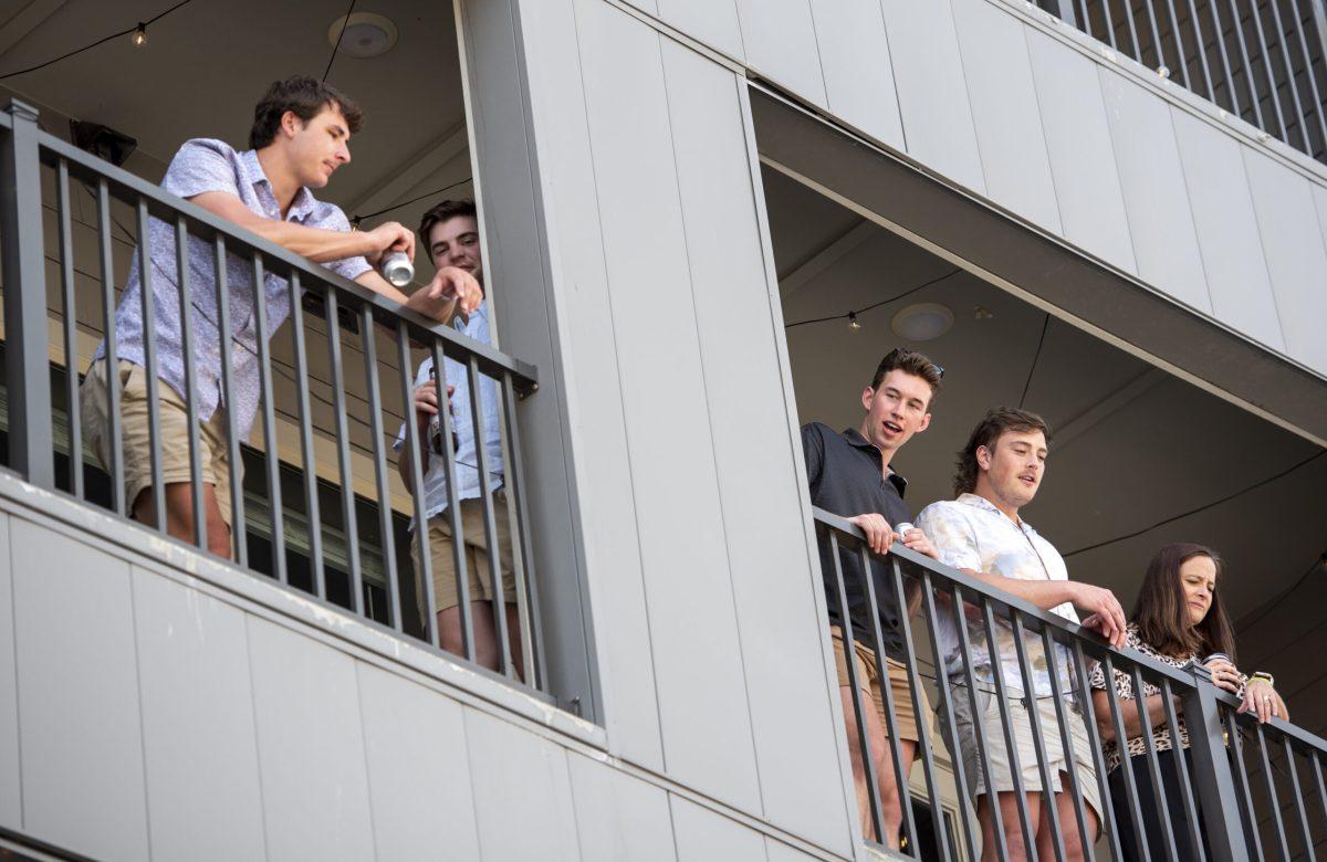 A group of people watch the protest from a balcony.
