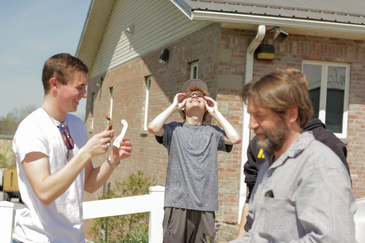 Boy smiling as he looks at the sky through eclipse glasses.
