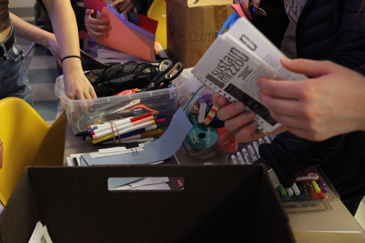 Students reach into containers of supplies.