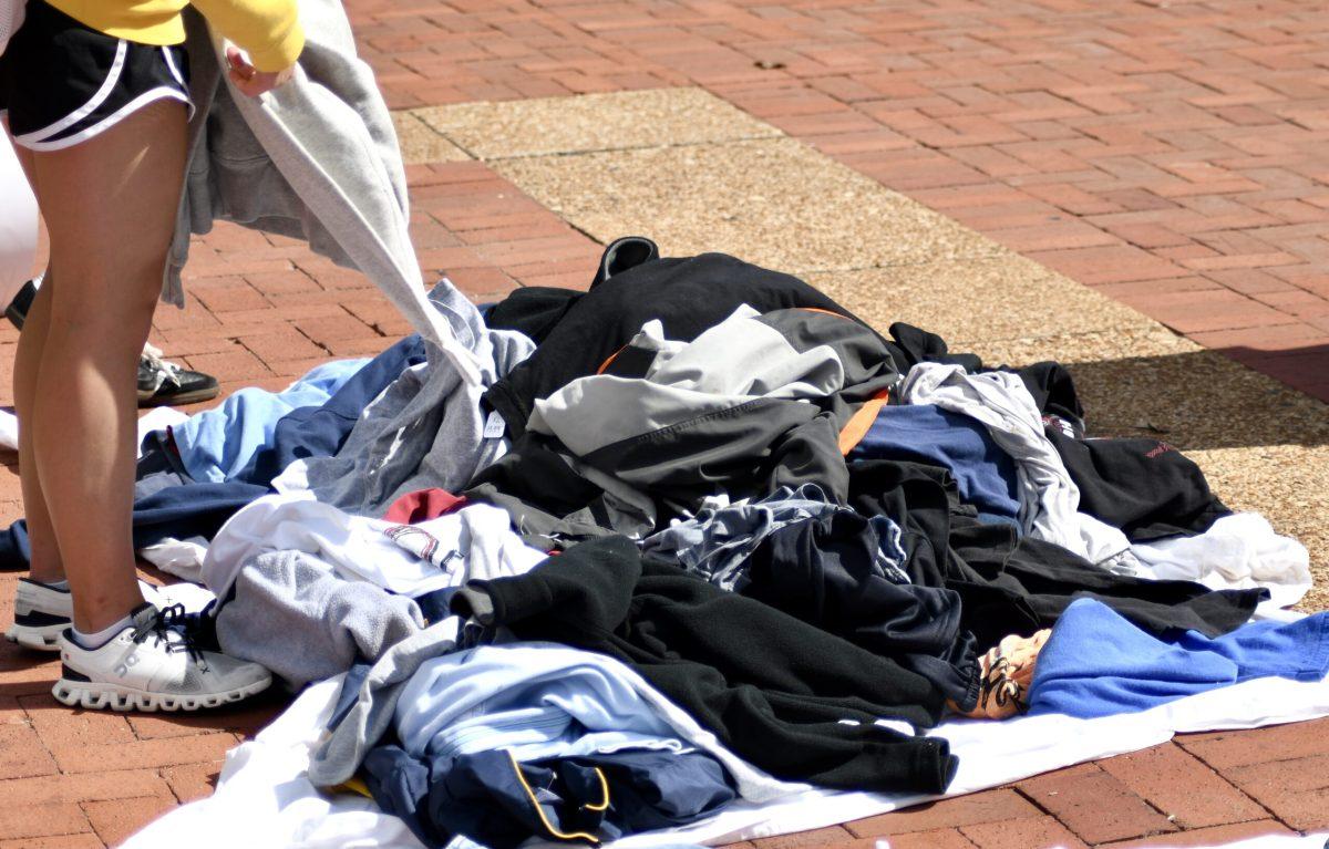 A pile of sweatshirts lying on top of a blanket on the ground.