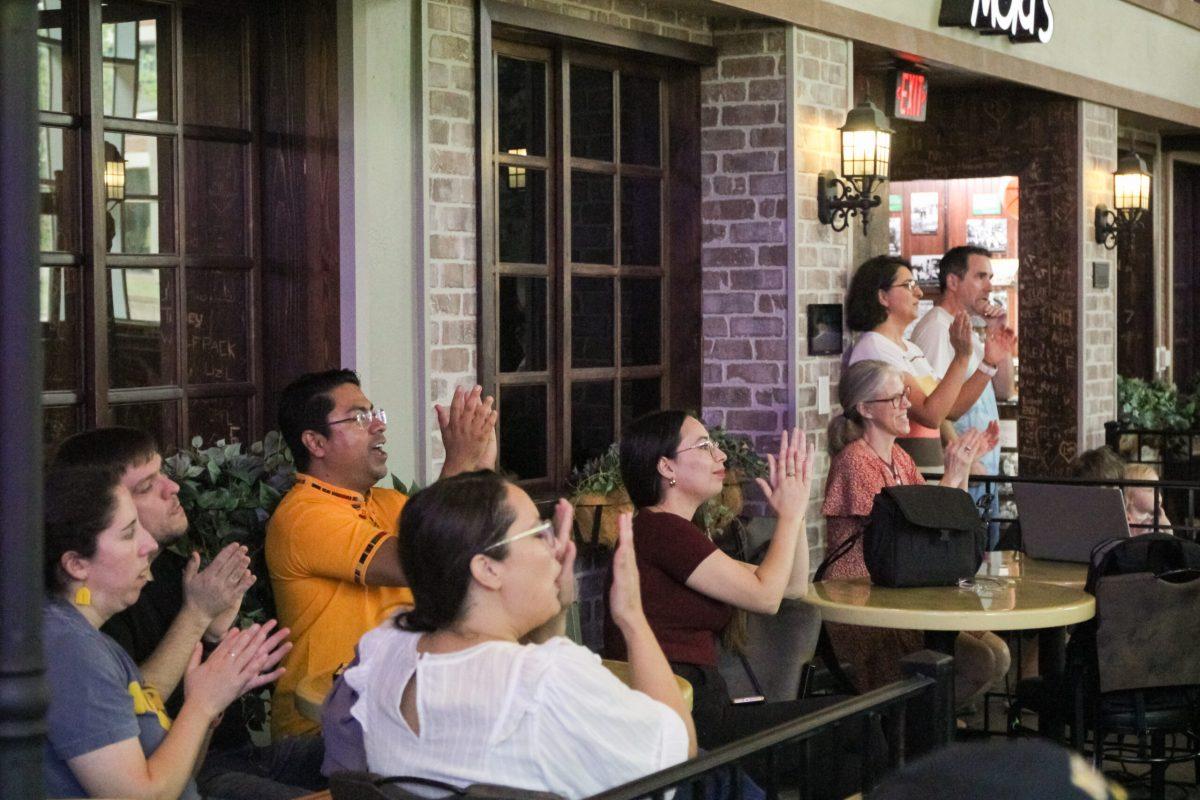 Several people clapping while watching a performance.