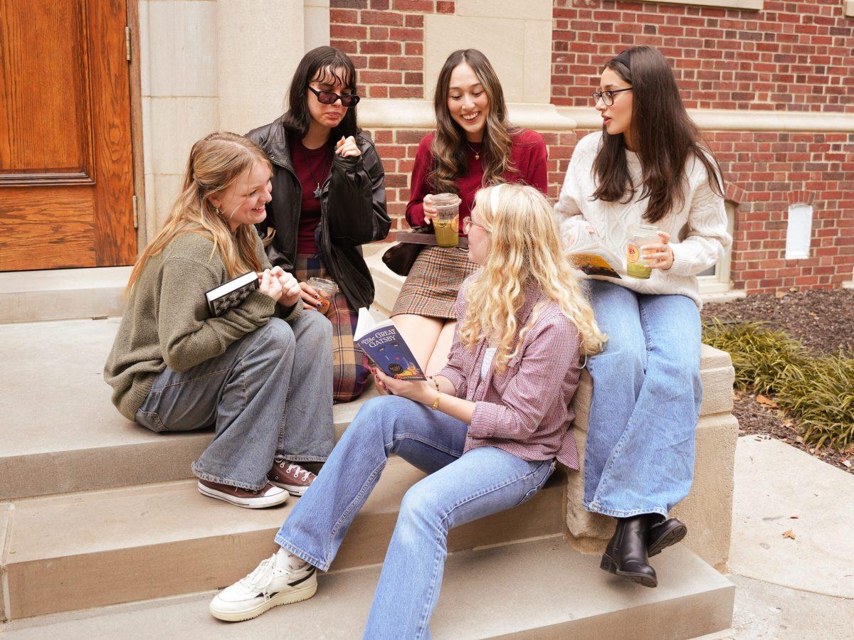 Five girls talking while sitting on a set of steps.