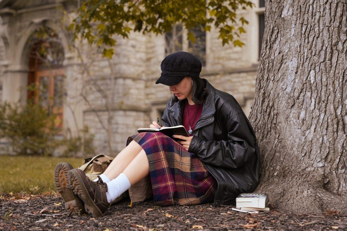 A girl journaling while sitting underneath a tree.