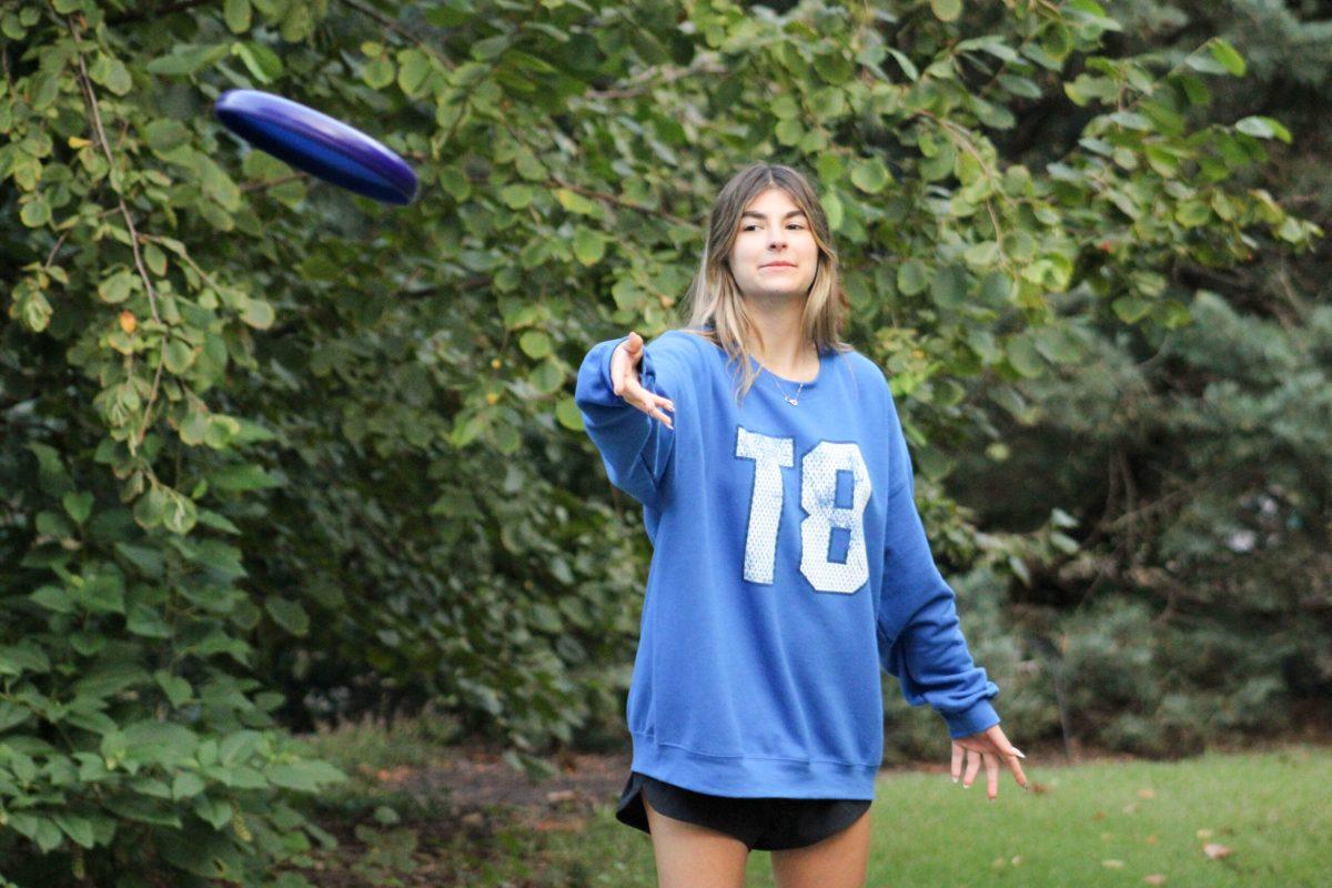 A student throwing a frisbee to her friend.