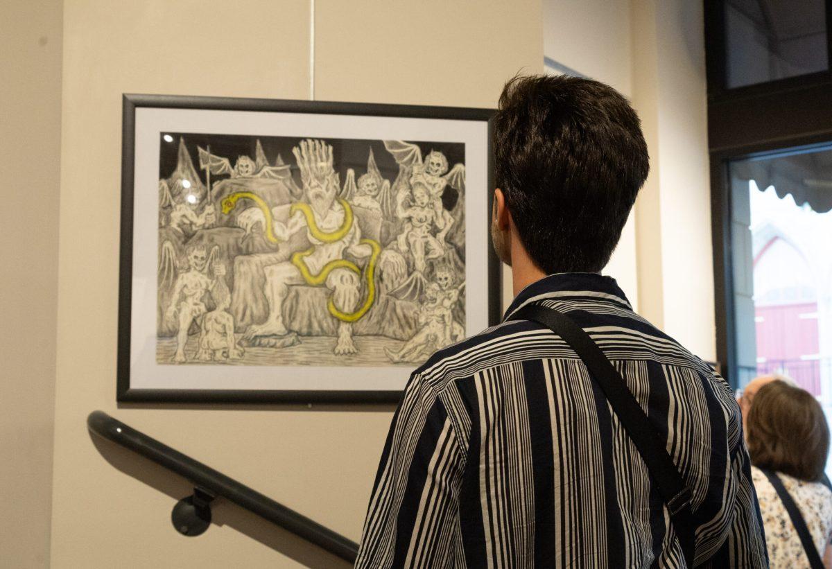A man standing in front of a framed painting displayed on a wall.
