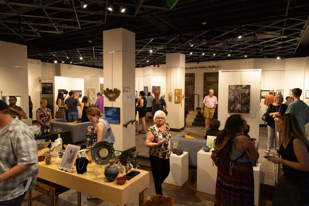 Many people walking around the art gallery.