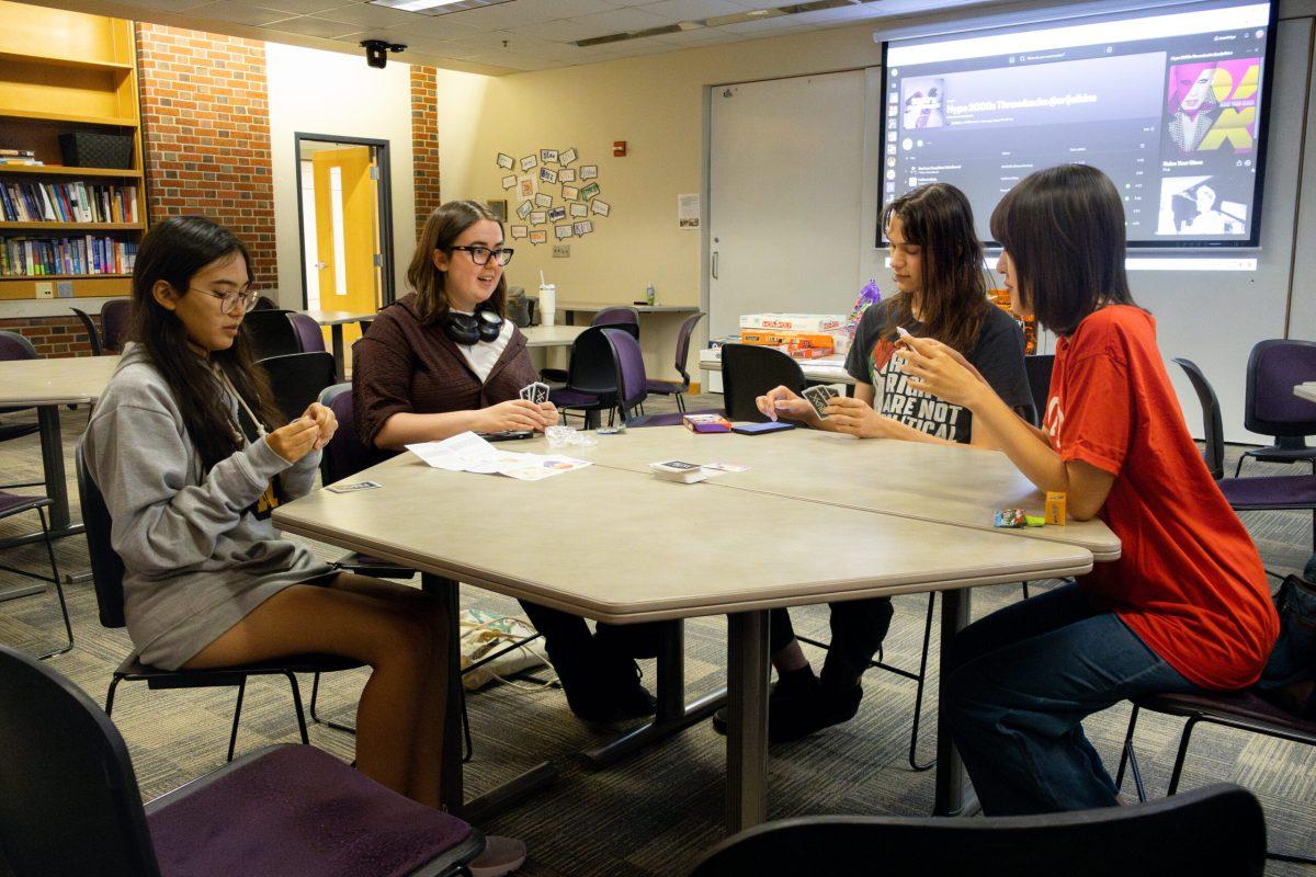 Four students sitting around a table playing a card game.