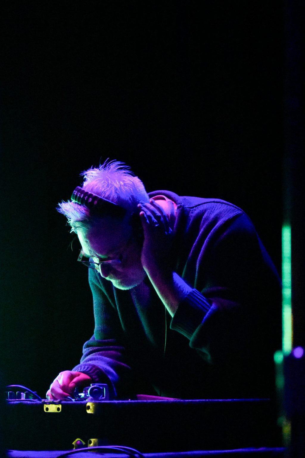 A man stands over a DJ booth.