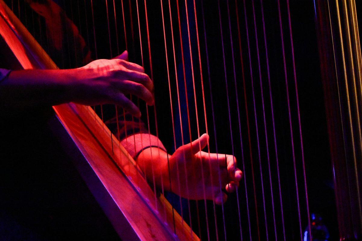 A man’s hands play a harp.