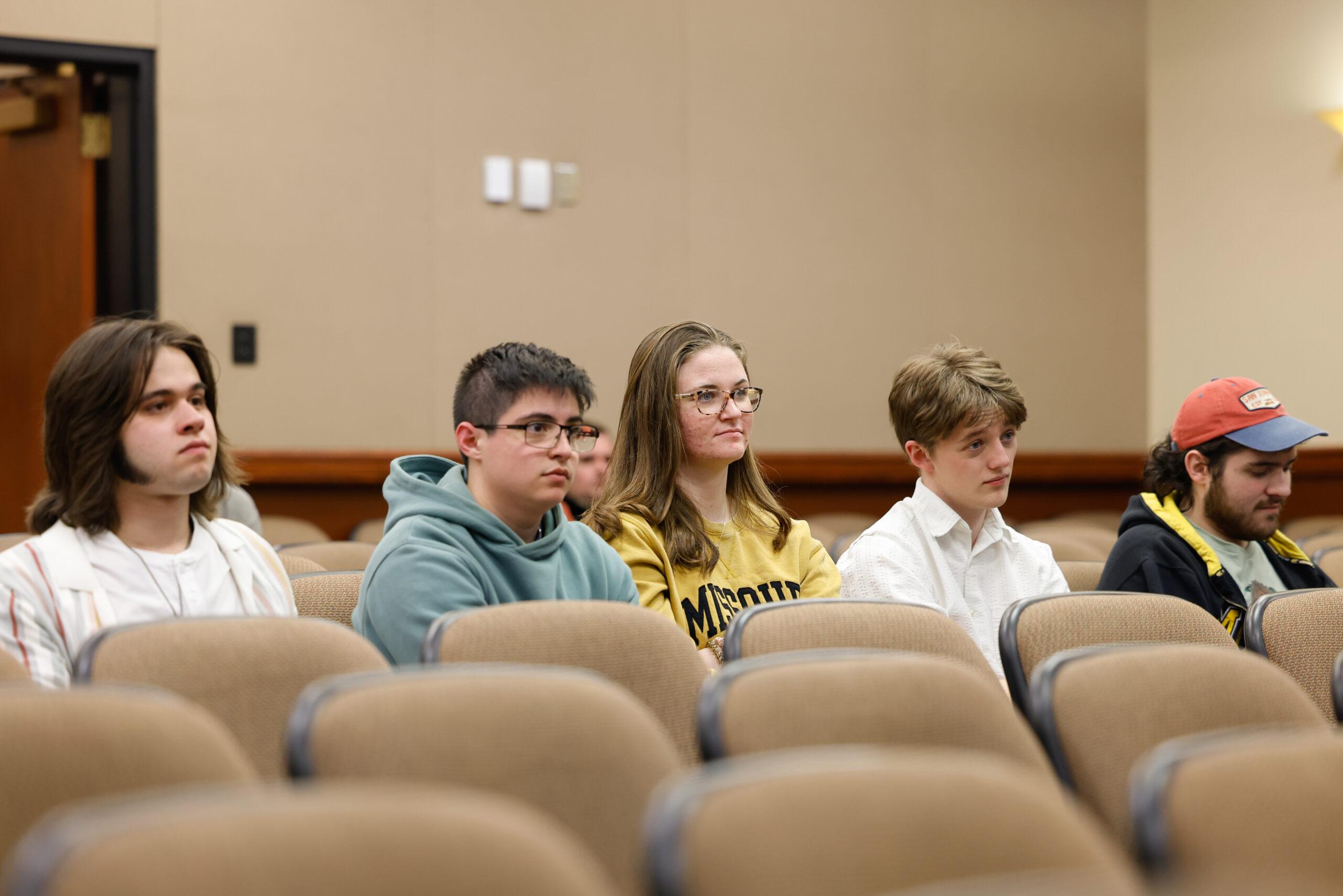 Five people watching a forum from the audience.