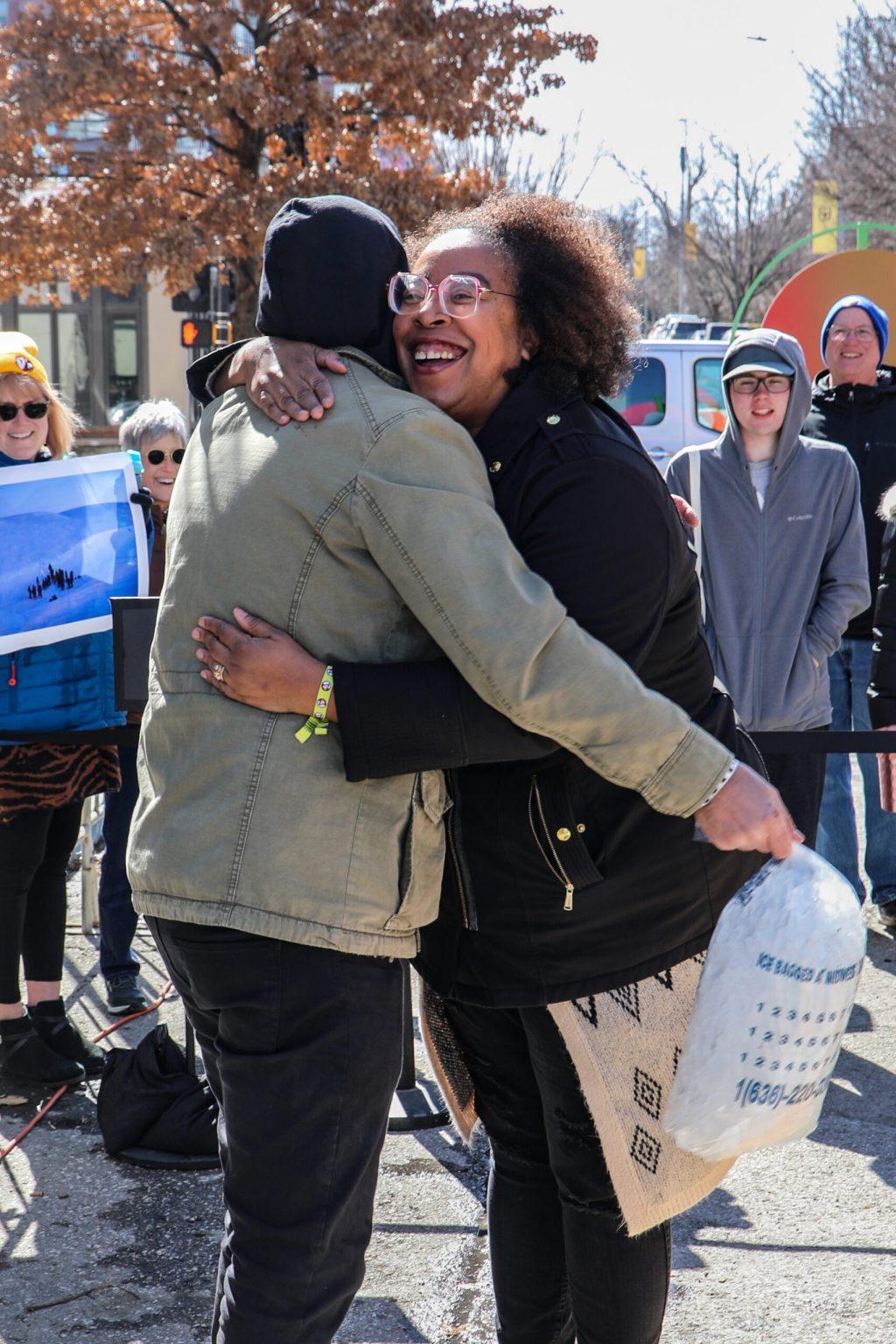 Two people hug in front of a crowd.