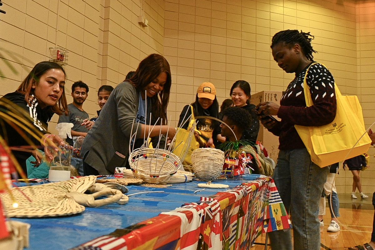 Mildred Emegha, president of Women Economic Empowerment @ Mizzou, helps teach basket weaving to passersby at MU’s Global Bazaar on Friday, April 11, 2025, in Columbia, Mo. “What we are exhibiting is basket weaving, it’s a traditional art that is known to the Native Americans… It takes two weeks to learn this skill, but they did it in under 20 minutes,” Emegha said.