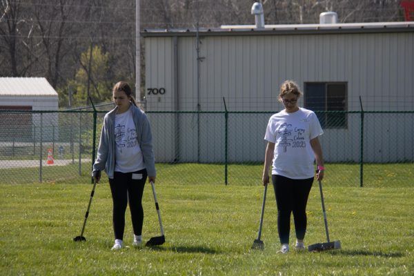 Two people walking in a field scooping up dog poop.