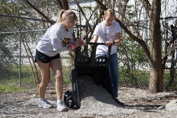 People dumping a wheelbarrow of gravel.