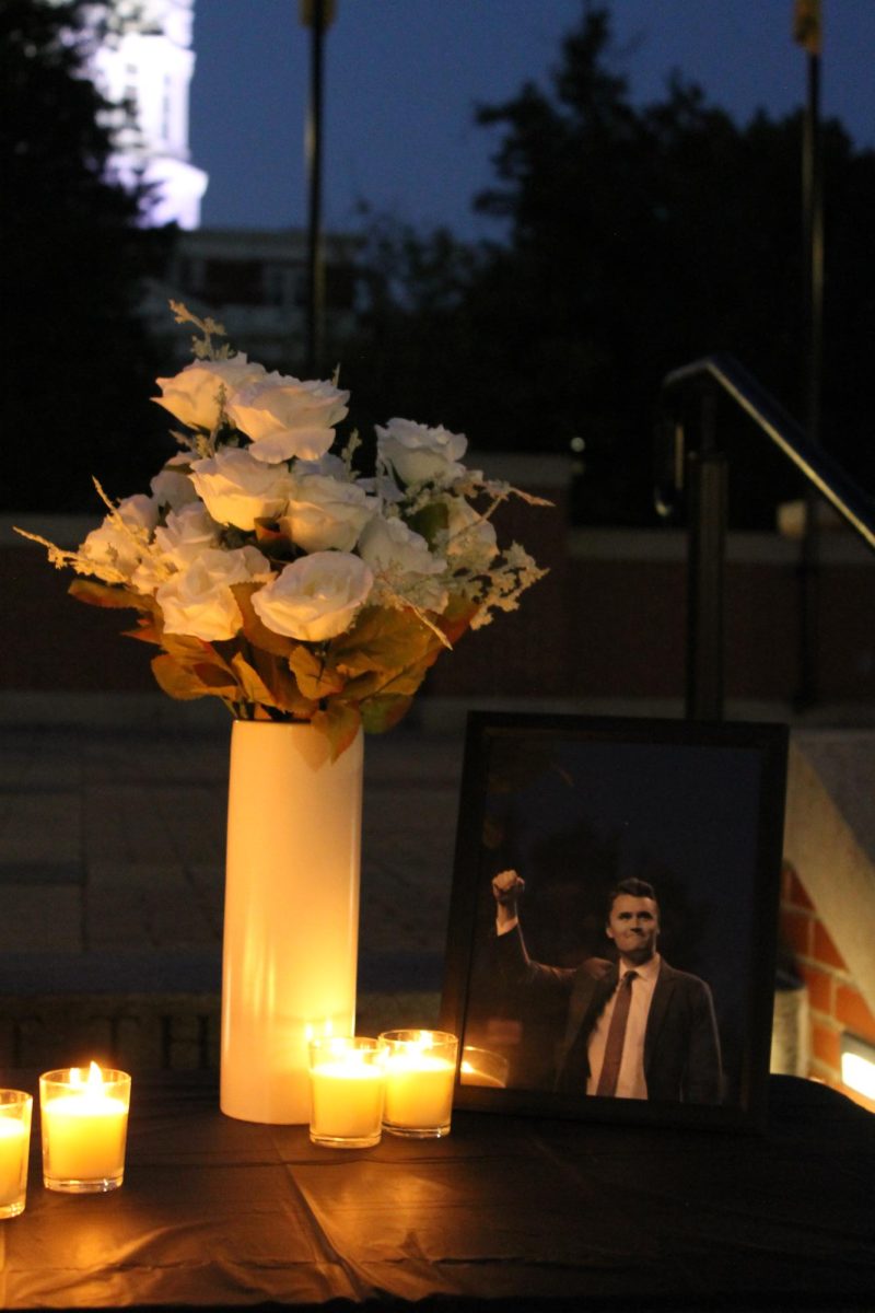 A candlelit table, vase of white roses and framed photo of conservative speaker Charlie Kirk sit in the center of Traditions Plaza on Wednesday, Sept. 10, 2025, in Columbia, Mo. MU’s Turning Point USA chapter hosted a vigil to grieve Kirk.