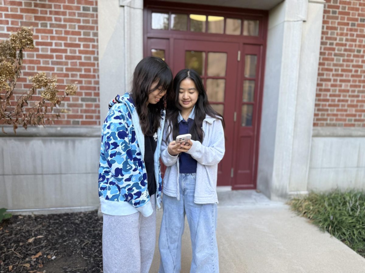 International students Daisy Zhan and Selina Wang, both third-year journalism students, scroll through Zhan’s phone outside of Tate Hall on Thursday, Sept. 25, 2025 in Columbia, Mo. The roommates stay in touch with family in China using text messages and phone calls over WeChat.