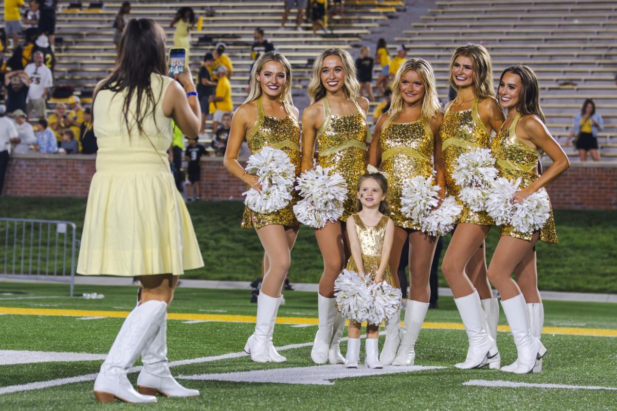 Four women and one girl in sparkly gold outfits pose for a photo together