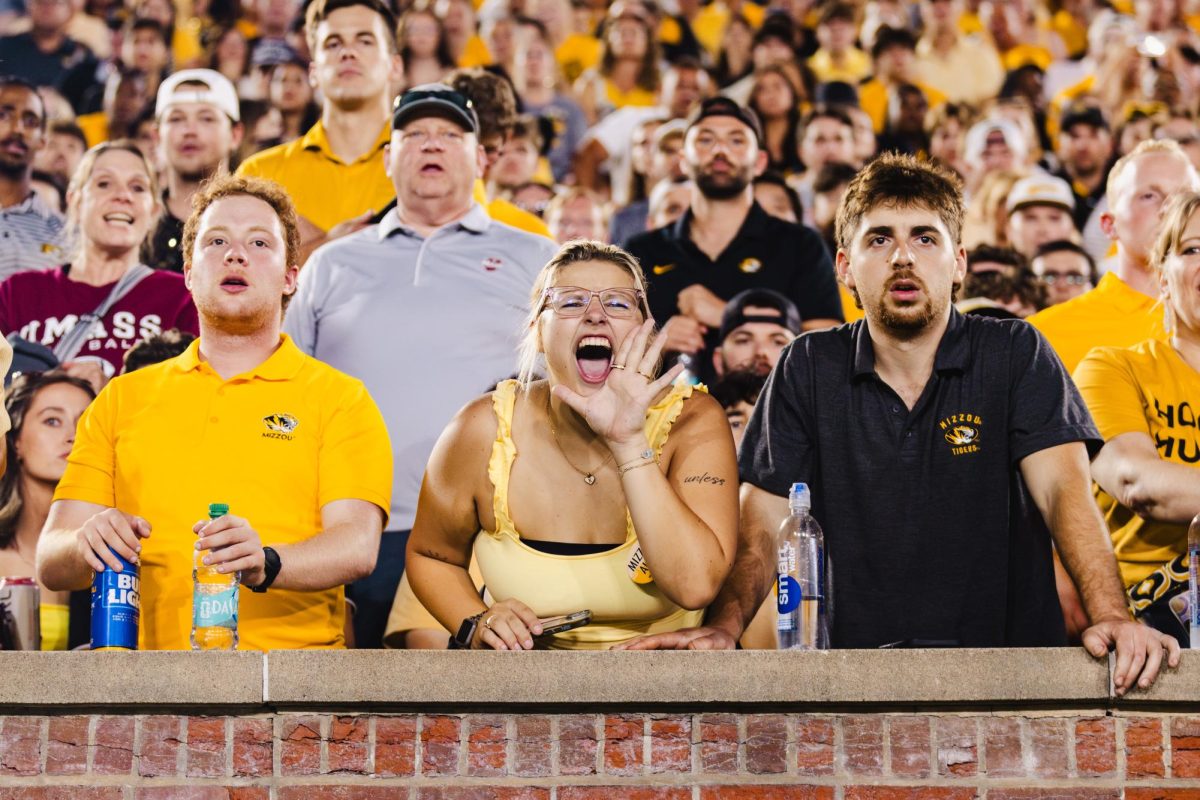 Two men watch a game on either ends of a woman screaming
