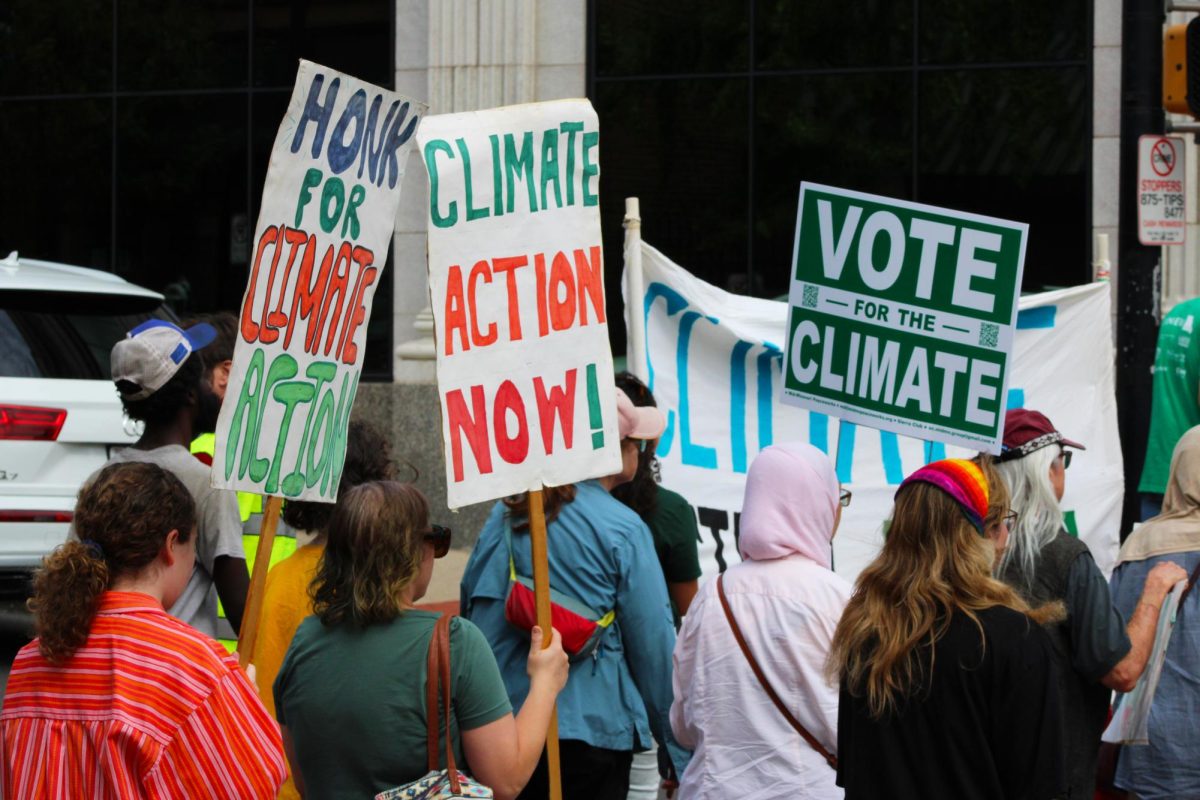 Marchers hold signs as the “Walk for the Climate” makes its way through downtown Columbia on Sunday, Sept. 21, in Columbia, Mo. One sign reads “Climate Action Now!” as another says “Vote for the Climate.”