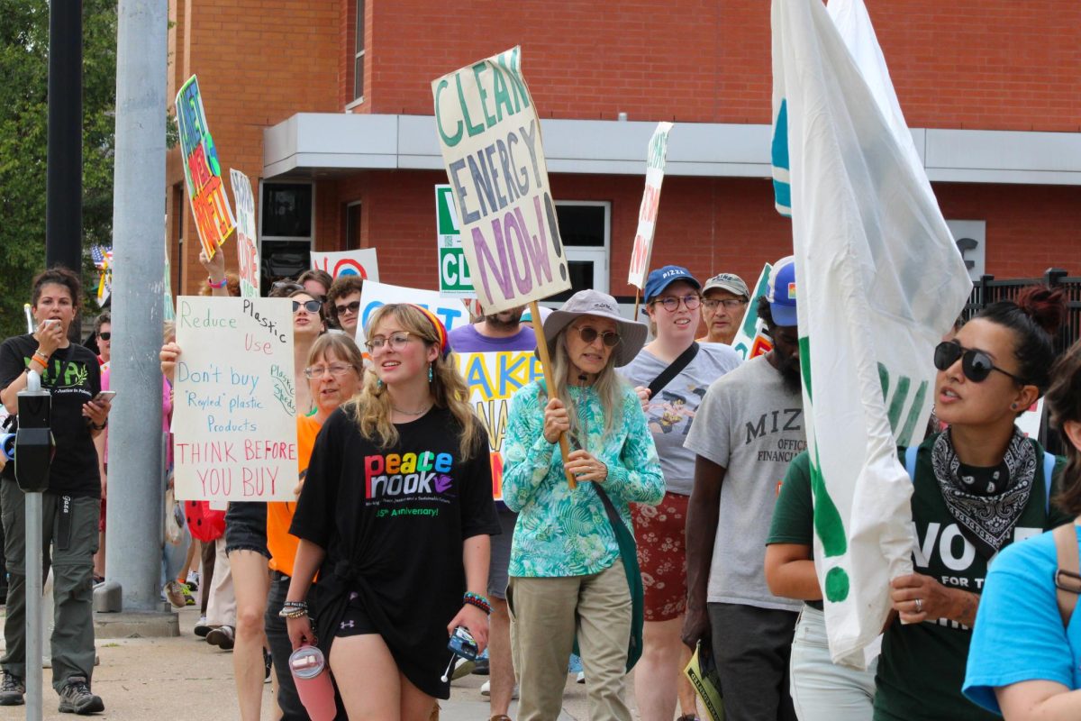 A column of climate protestors waves signs and banners from the sidewalk on Sunday, Sept. 21, in downtown Columbia, Mo. Leading chants is Rasha Abousalem, a humanitarian aid worker, member of Missourians for Justice in Palestine, and adjunct professor at the University of Missouri.