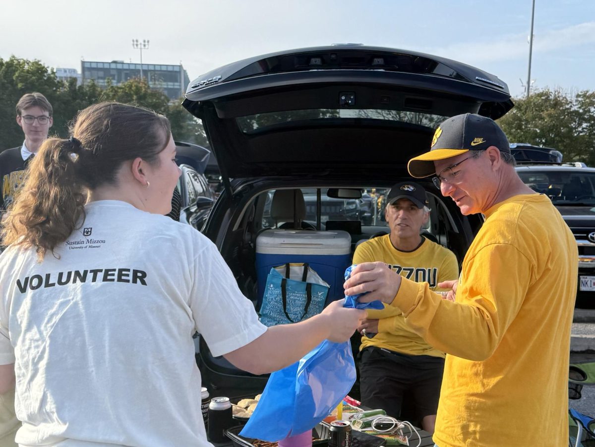 First-year student Kate Tyson hands a recycling bag to a tailgater before the Missouri vs. Alabama football game on Saturday, Oct. 11 in Columbia, Mo. Tyson and other Tiger Tailgate Recycling volunteers split up to cover several parking lots, offering a bag for recyclables to each tailgate they saw. 