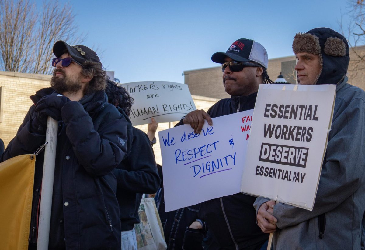 While holding signs, demonstrators listen to Kevin Perkins during the MU Workers Rally on Friday, February 6, in Speakers Circle in Columbia, Mo.  Perkins announced at the rally that he had officially retired from MU after working there for the past five years. 