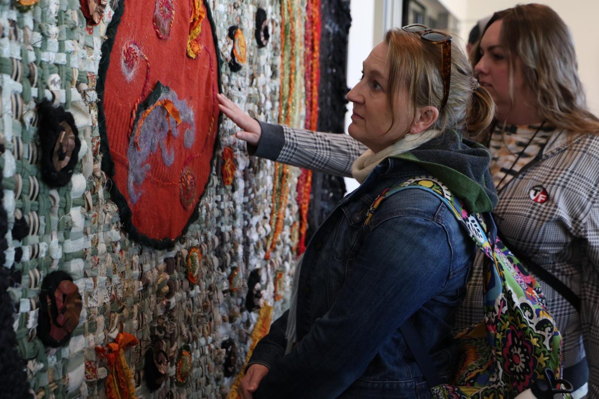 Art Walk attendees look at the art piece “Unfound Tapestries” on Sunday, March 8 at the Picturehouse in Columbia, Mo.  These tapestries were created by multiple artists to represent maps impact humans